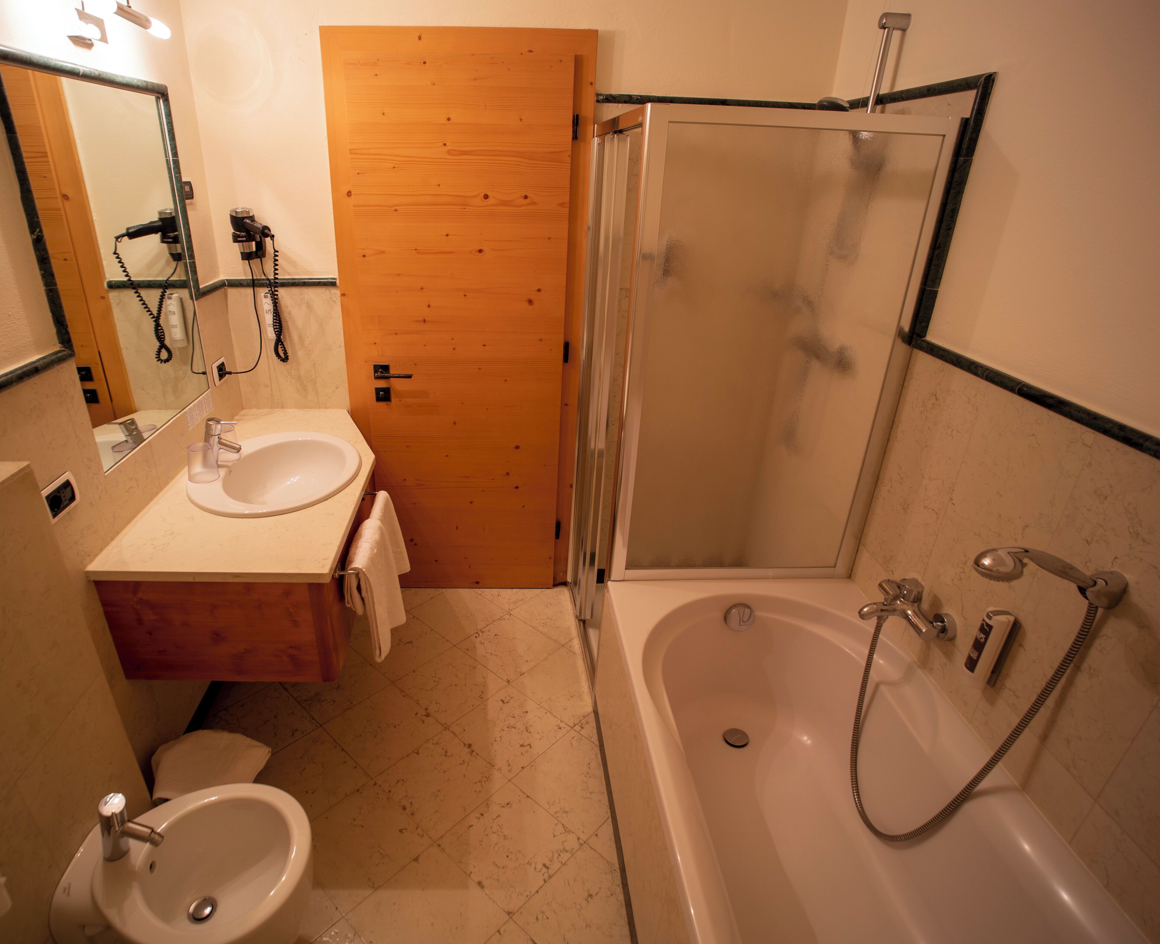 A bathroom with a sink, mirror, toilet, and shower area.