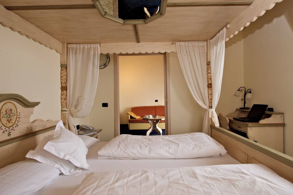 A hotel room with a bed, a nightstand, a lamp, and a view of the hallway.