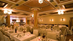 A banquet hall with multiple round tables set for dining, each with white tablecloths and candles. - Hotel Touring Livigno (Livigno)