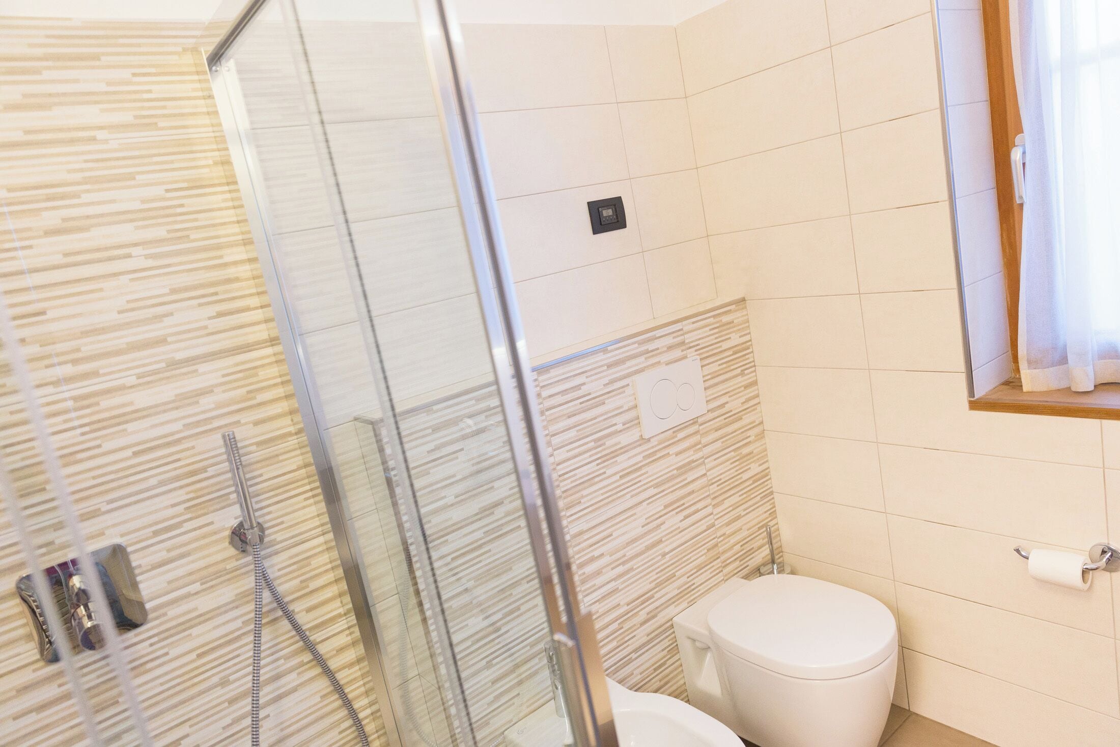A bathroom with a glass-enclosed shower, a toilet, and a towel rack.