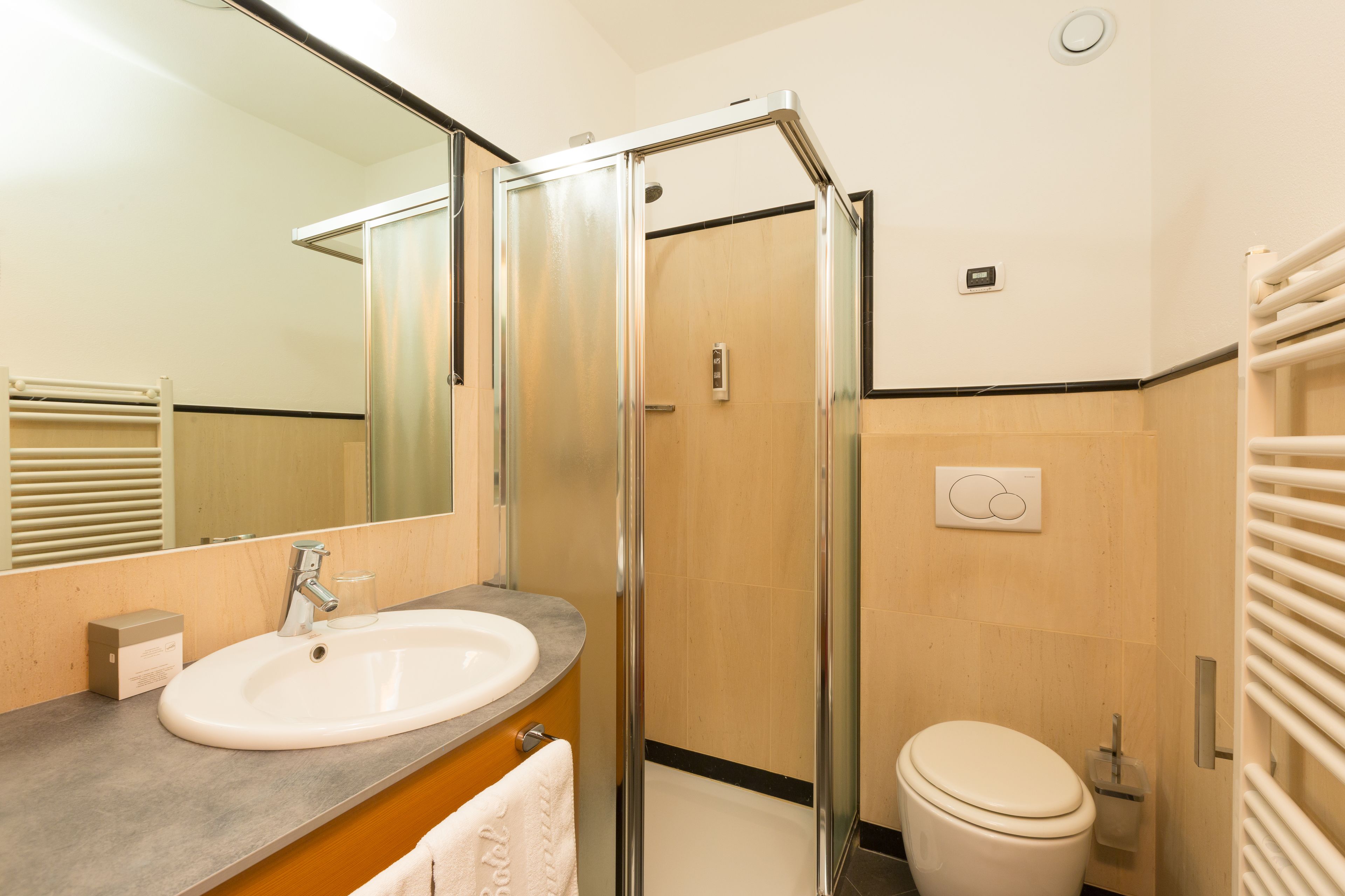 Un baño moderno con ducha de vidrio, lavamanos y retrete.