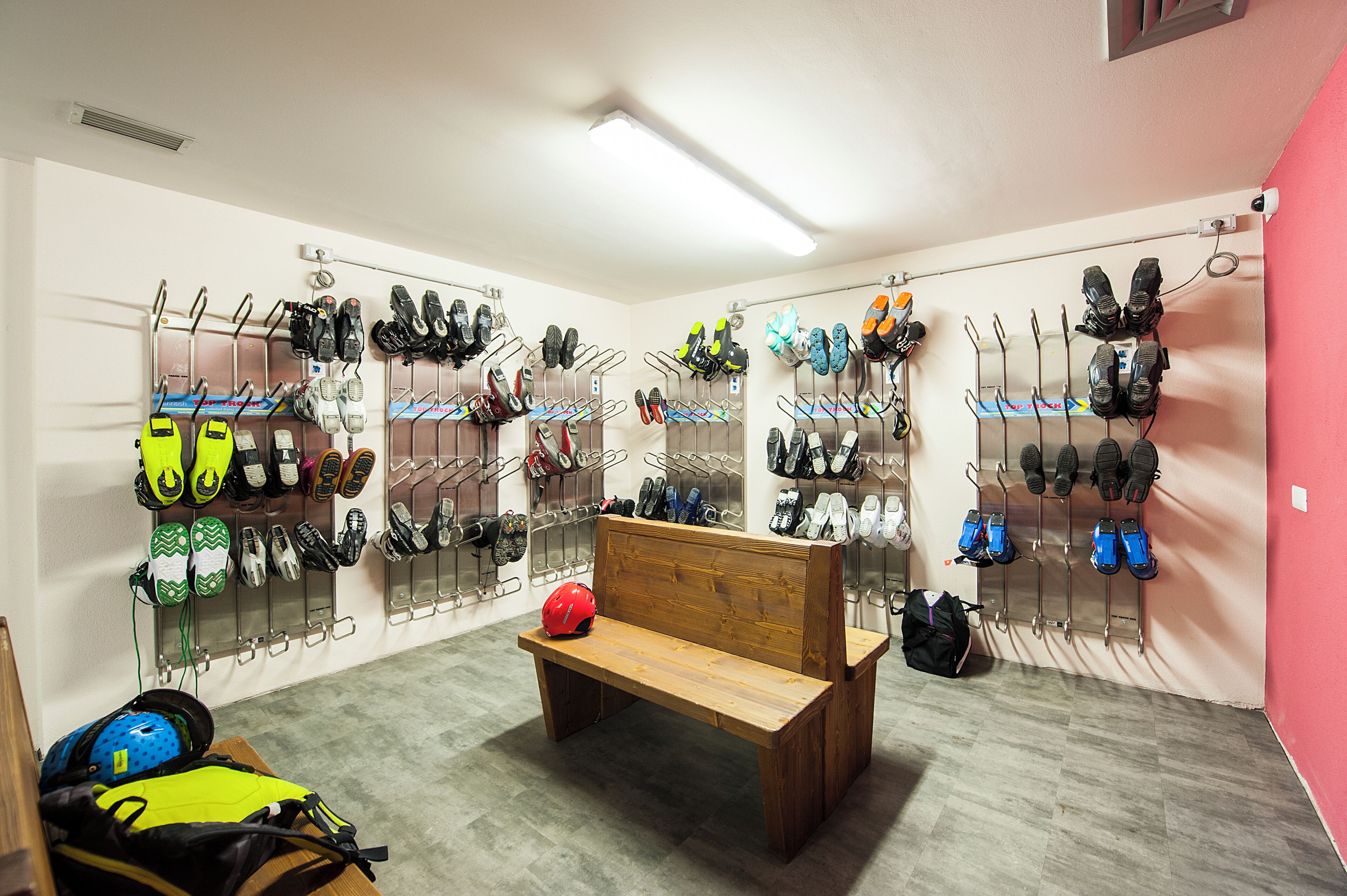 Un espace de rangement pour les chaussures, avec plusieurs étagères, un banc et un casque posé sur le sol.