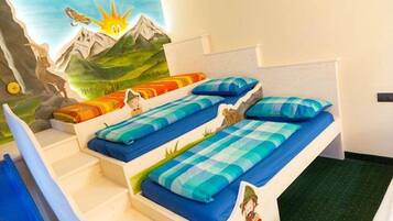 Una cameretta con un murale raffigurante un paesaggio montano, un letto con biancheria azzurra e una piccola scala.