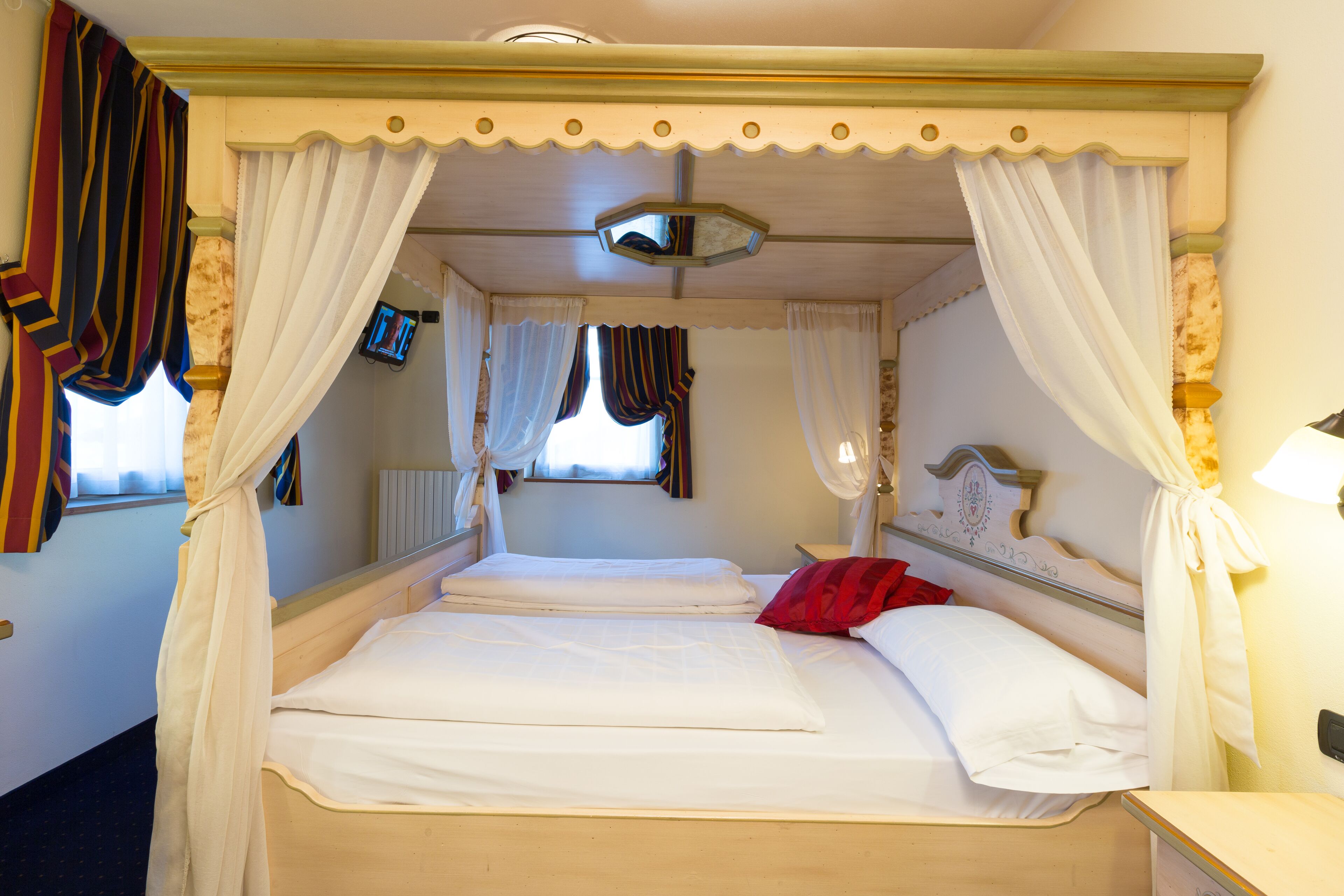 Een bed met witte lakens, een rode kussen en een hemelbed.