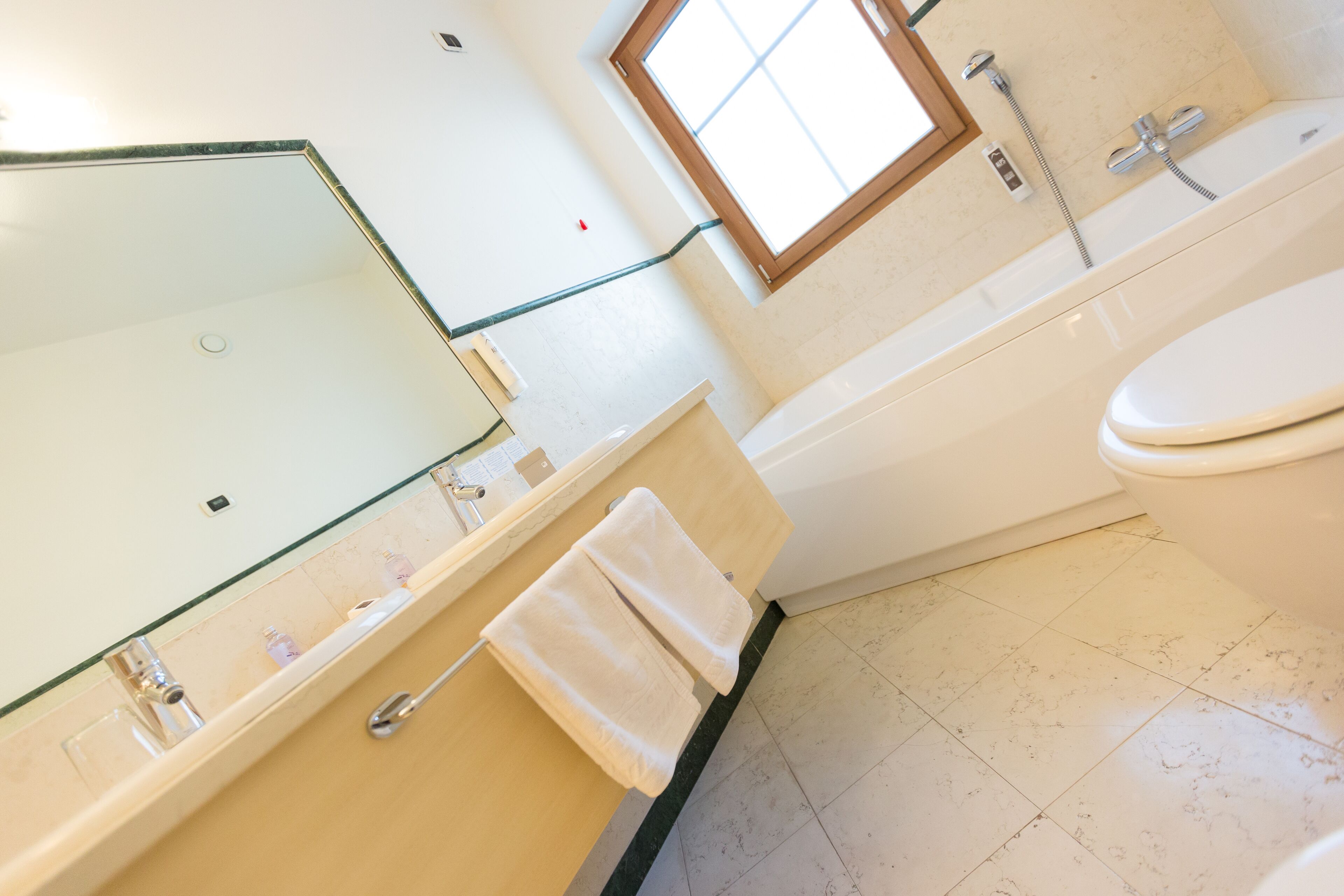 A bathroom with a bathtub, toilet, and a glass-enclosed sink area.