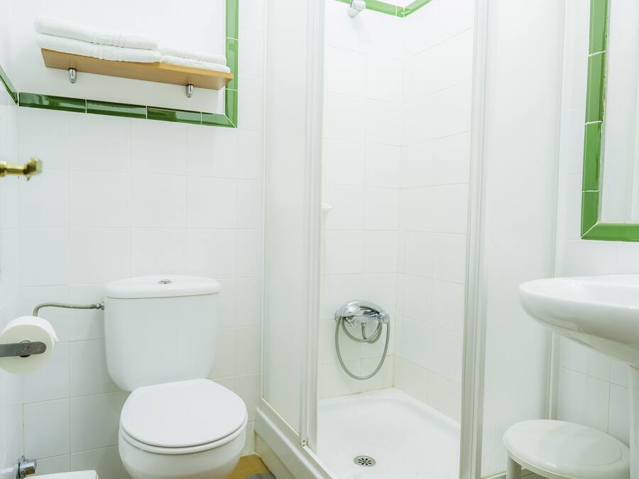 A bathroom with a toilet, shower, and sink.