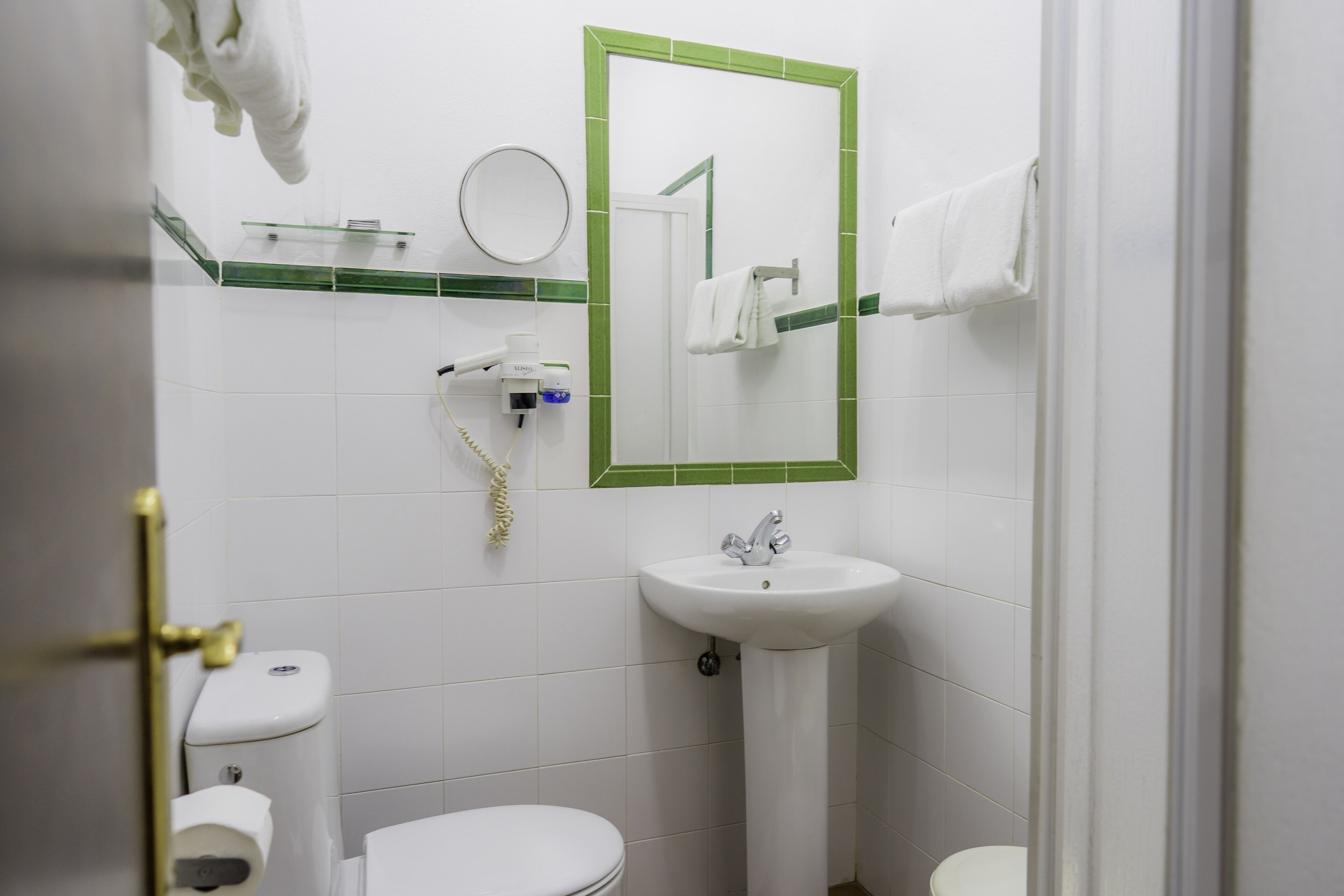 A bathroom with a toilet, sink, and mirror.