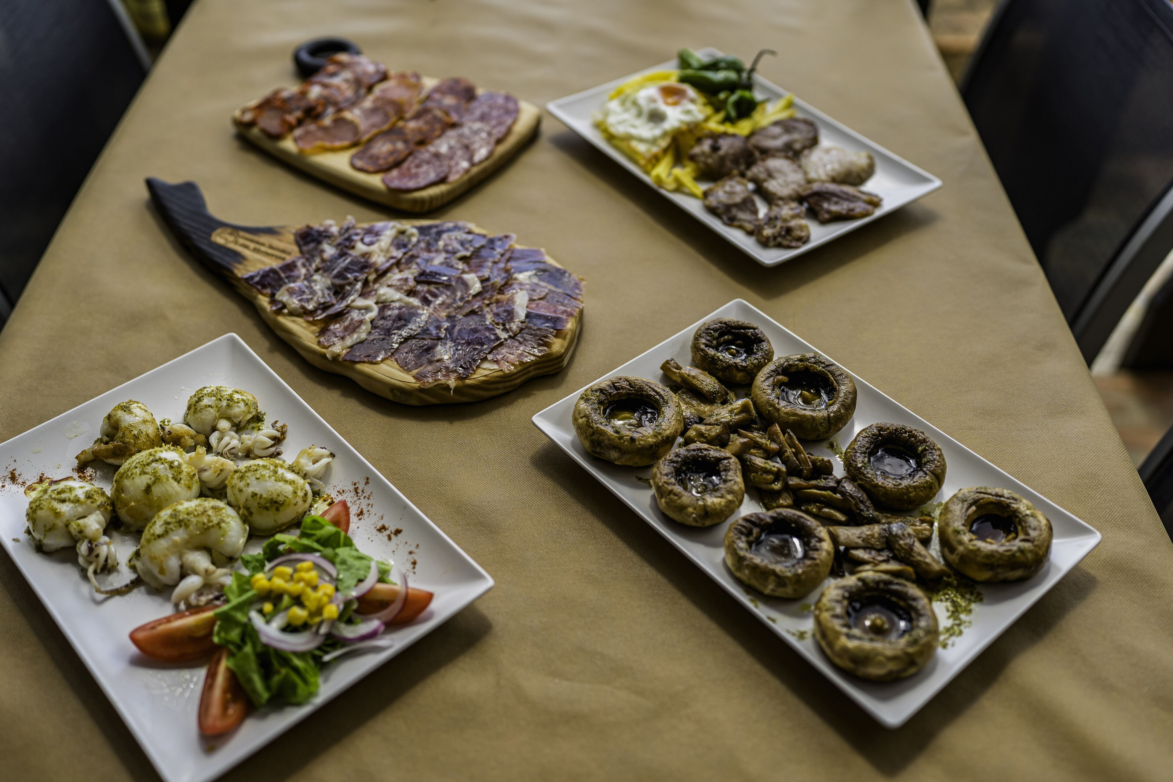 Una taula plena de diferents plats, com pizza, amanides i altres aperitius.
