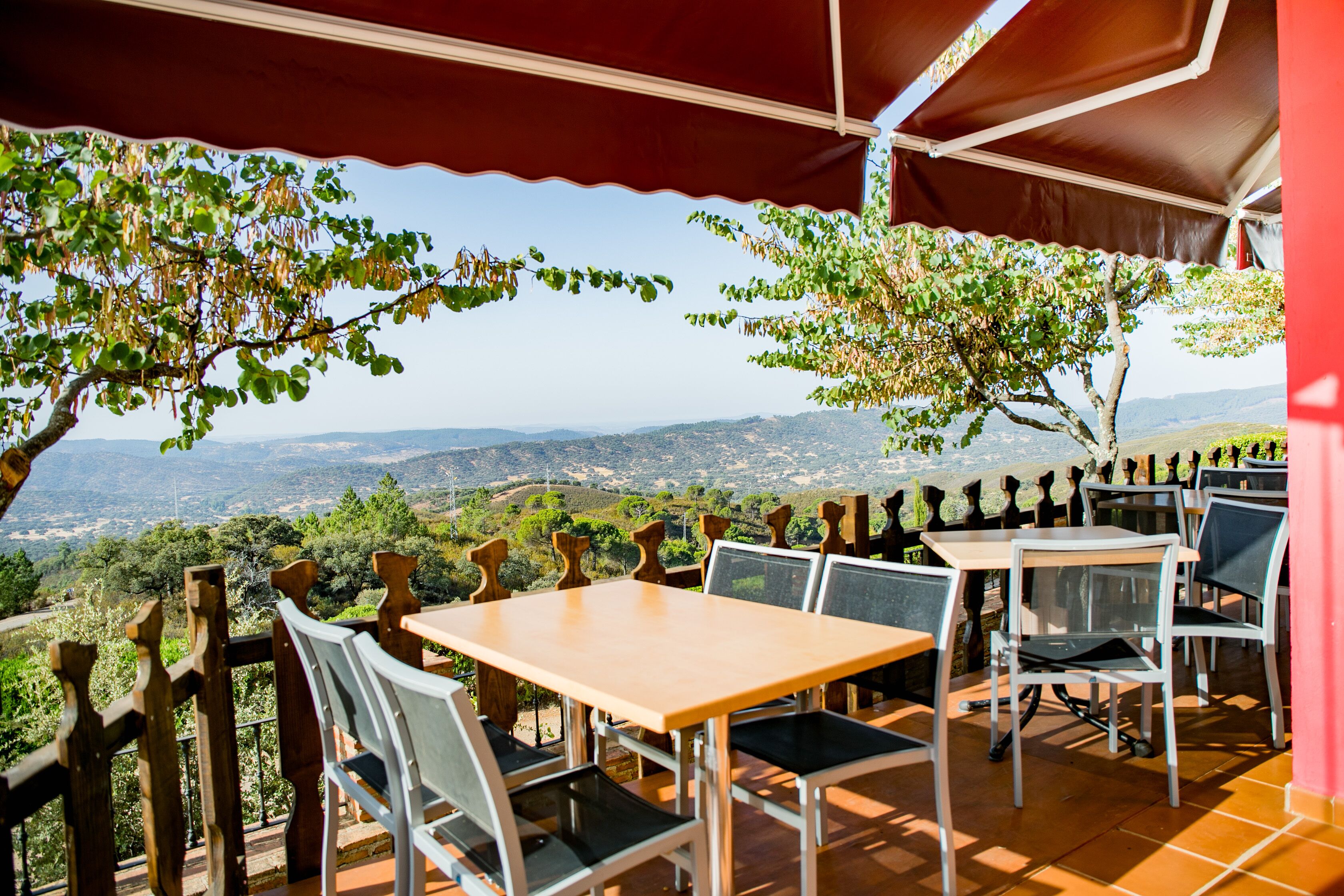 An outdoor patio with tables and chairs, overlooking a scenic landscape.