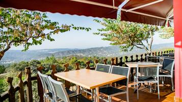 An outdoor patio with tables and chairs, overlooking a scenic landscape.