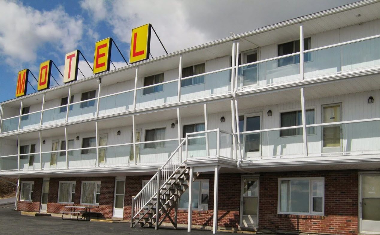 A motel with a two-story structure, multiple windows, and a prominent 'MOTEL' sign.