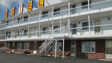 A motel with a two-story structure, a covered parking area, and a staircase leading to the entrance.