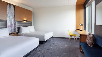 A hotel room with two beds, a desk, a chair, and a sofa.