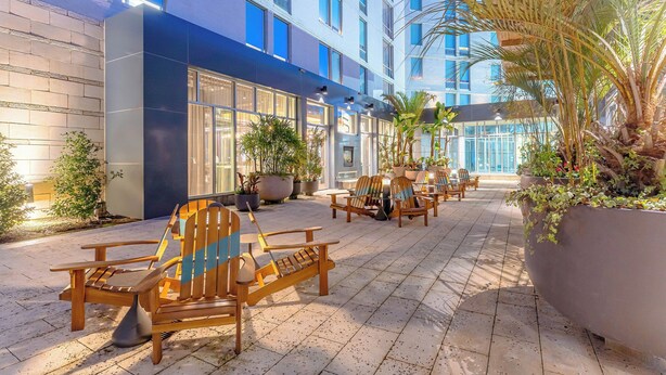 A hotel courtyard with outdoor seating, potted plants, and a modern building facade.