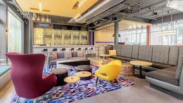 A modern lounge area with seating, a bar, and large windows.