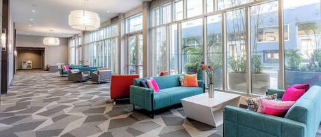 A spacious lobby with large windows, modern furniture, and a geometric carpet pattern.