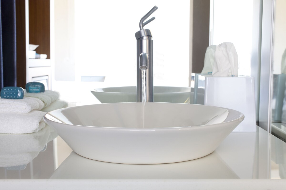 A modern bathroom with a large white sink, a faucet, and a mirror.