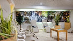Un espace d’attente avec des chaises, un comptoir d’accueil et une grande fresque murale représentant une cascade.
