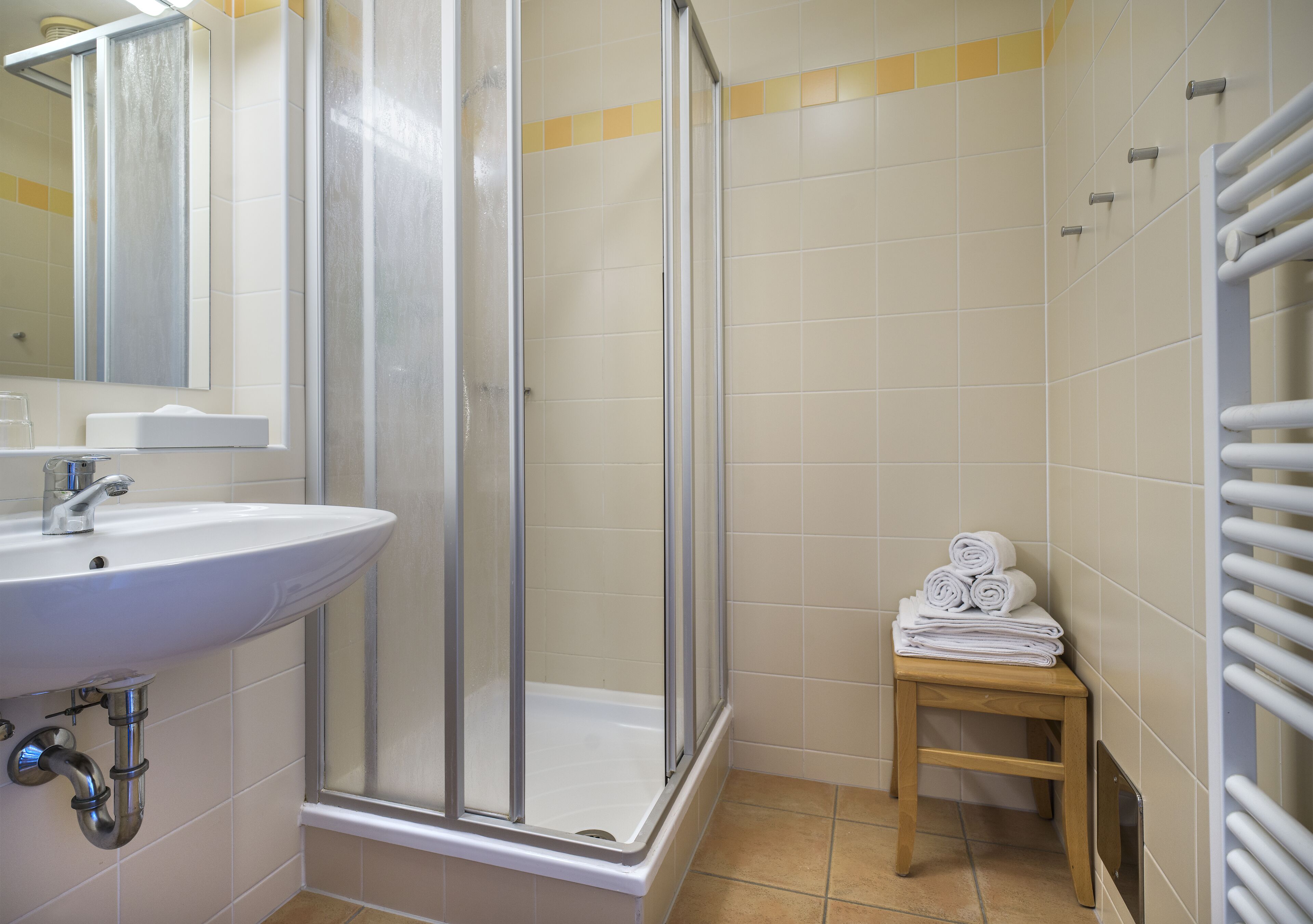 Ein Badezimmer mit Waschbecken, einer Duschkabine und einem Handtuchhalter.