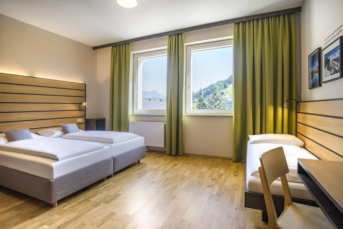 Habitació d'hotel amb dos llits, un escriptori i vistes a un paisatge muntanyós.