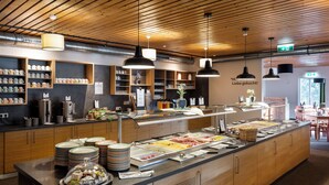 Un espace buffet proposant une variété de plats, un coin café et un espace détente avec des tables et des chaises.