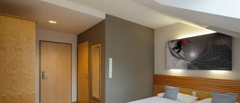 Habitación de hotel con dos camas, cabecero de madera, un cuadro en la pared y una puerta de madera.