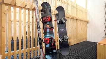Tres tablas de snowboard apoyadas contra una pared de madera en una habitación con piso de goma negra.