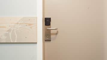 Une porte dotée d’un clavier numérique et d’une poignée, située à côté d’un mur recouvert d’un panneau de bois.