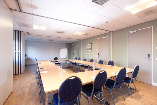 A conference room with a long table, chairs, and a whiteboard.