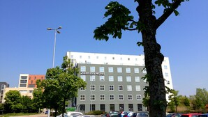 Un hôtel à plusieurs étages, doté d’une façade sobre, de nombreuses fenêtres et d’une enseigne bien visible indiquant « Zaan Inn Hotel ».
