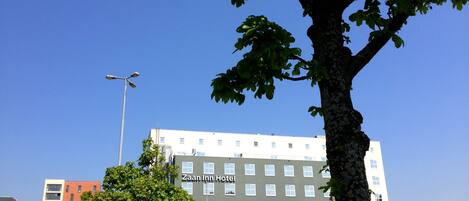 A multi-story hotel with a flat facade, numerous windows, and a visible sign for 'Zaan Inn Hotel'.
