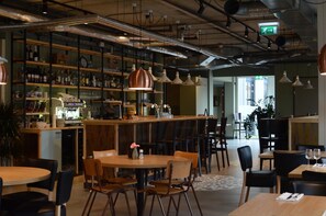 A restaurant with a bar area, wooden tables and chairs, and shelves stocked with bottles and glasses. - Best Western Zaan Inn, Amsterdam – Zaandam (Zaandam)