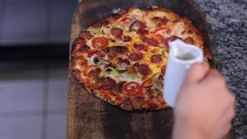 Una pizza sobre una tabla de madera en una cocina.