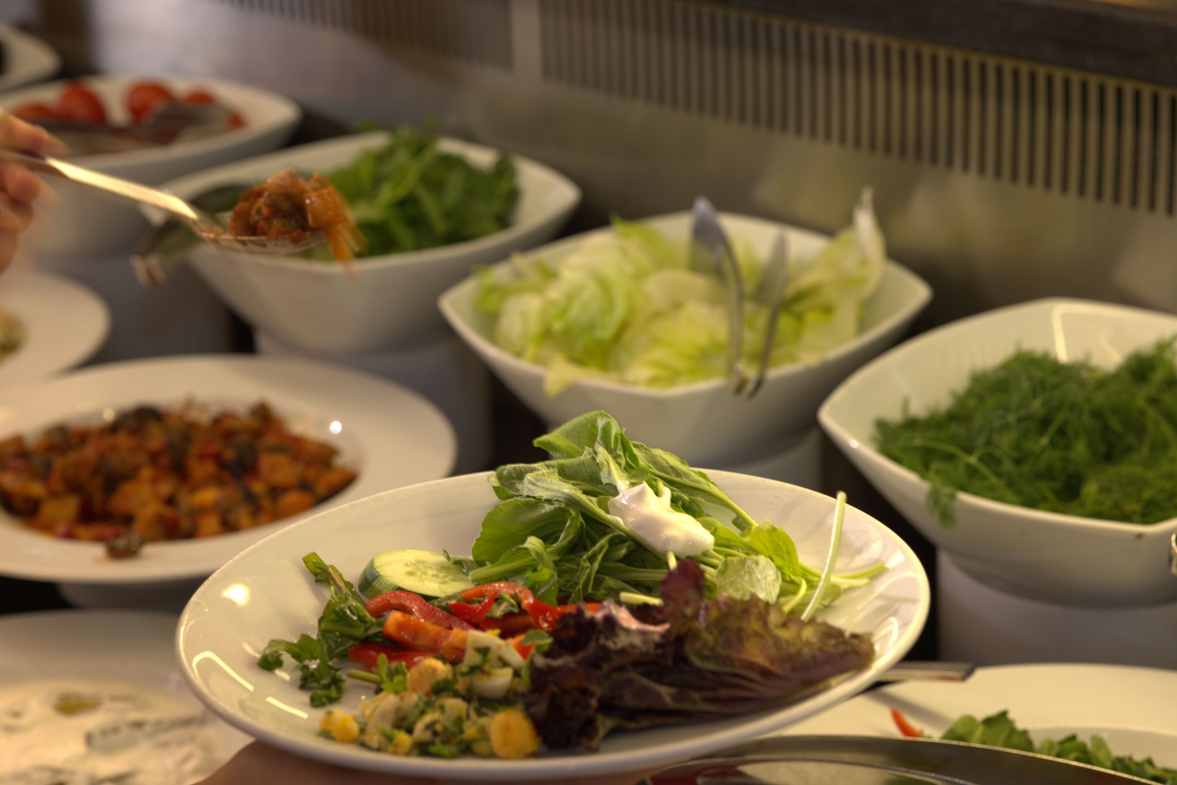 A buffet with various dishes including salads, vegetables, and a plate with a mixed salad.