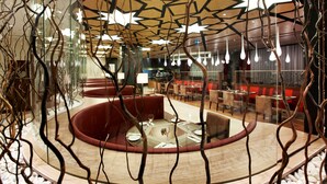 A modern restaurant with a central dining area, red cushioned seating, and hanging light fixtures. - Hilton Garden Inn Konya, Turkey (Konya)