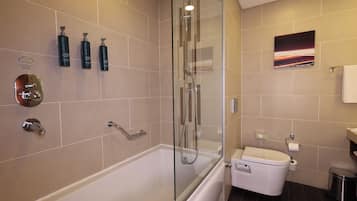 A modern bathroom with a glass-enclosed shower, a white bathtub, and a toilet.