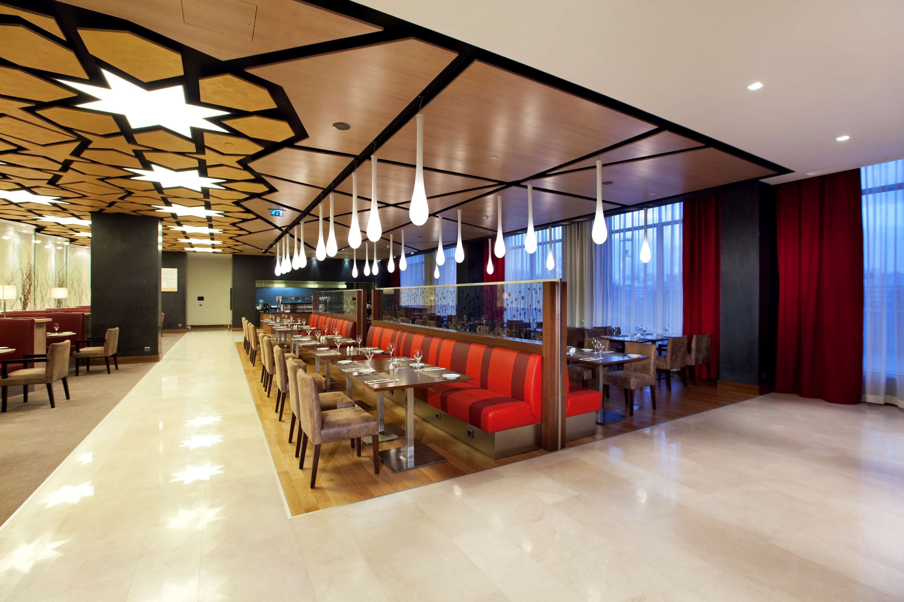 Un restaurant moderne avec un long comptoir, des sièges rouges et des lampes suspendues.