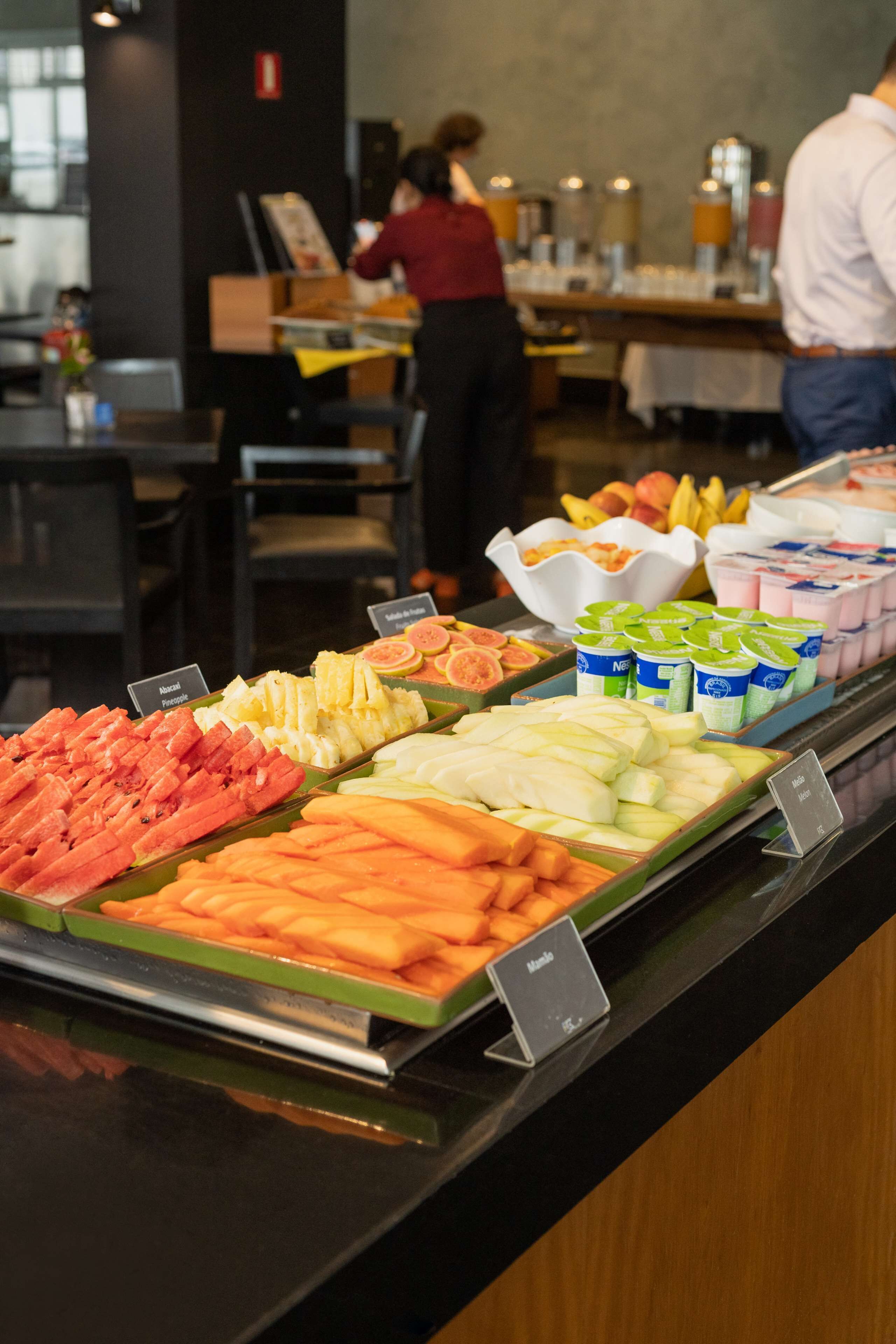 A buffet with various fruits and yogurt containers.