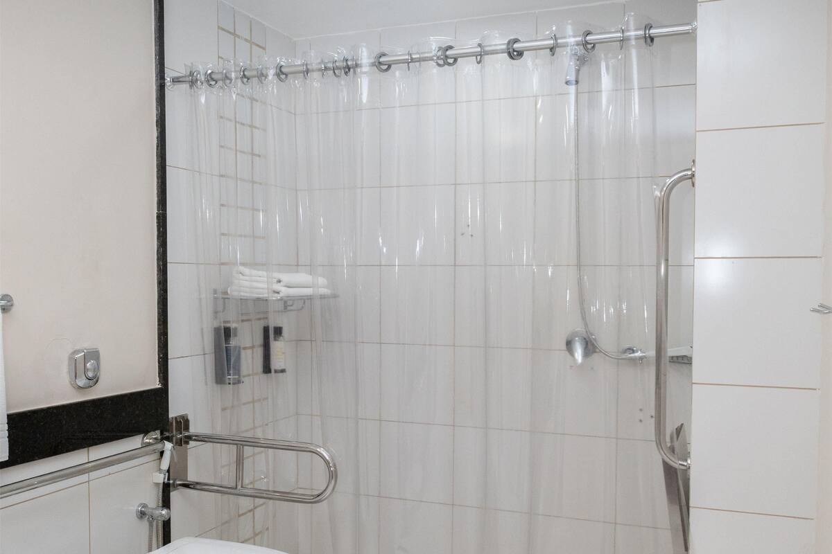 A bathroom with a shower, toilet, and a mirror.