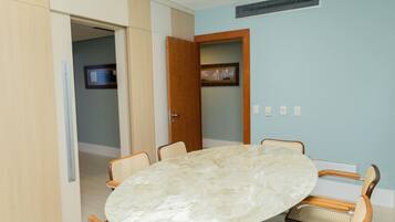 Un salón de conferencias con una mesa de mármol, sillas de mimbre y una puerta que da a otra habitación.