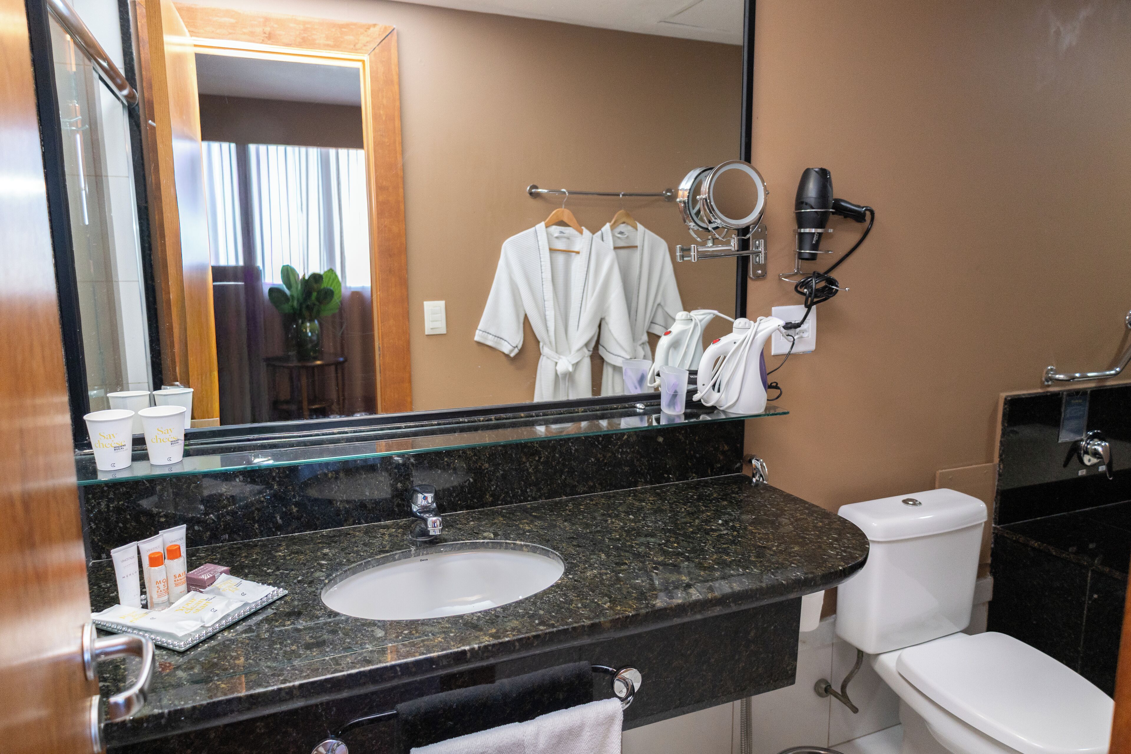 Casa de banho com lavatório, espelho, secador de cabelo e porta-toalhas.