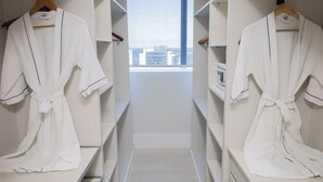 A walk-in closet with white shelves and a view of buildings through a window. - Golden Tulip Porto Vitória (Vitoria)