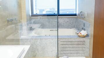 Un baño moderno con ducha envuelta en vidrio, una bañera grande y un tocador con espejo.