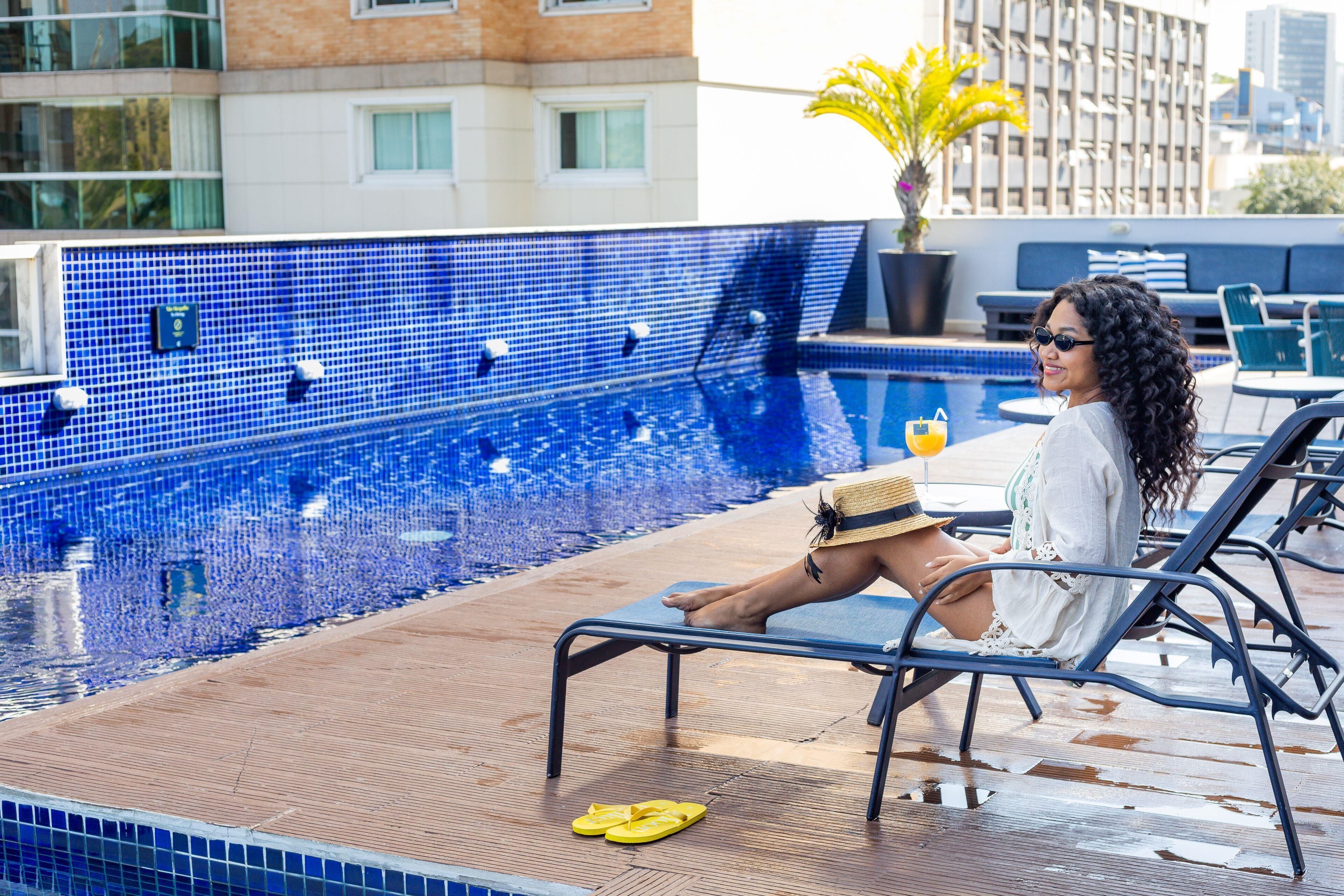 A poolside area with a tiled pool, lounge chairs, and a potted plant.