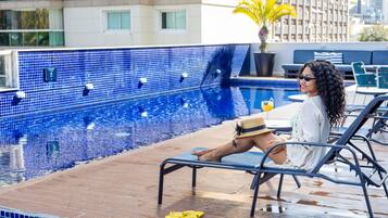 A poolside area with a tiled pool, lounge chairs, and a potted plant.