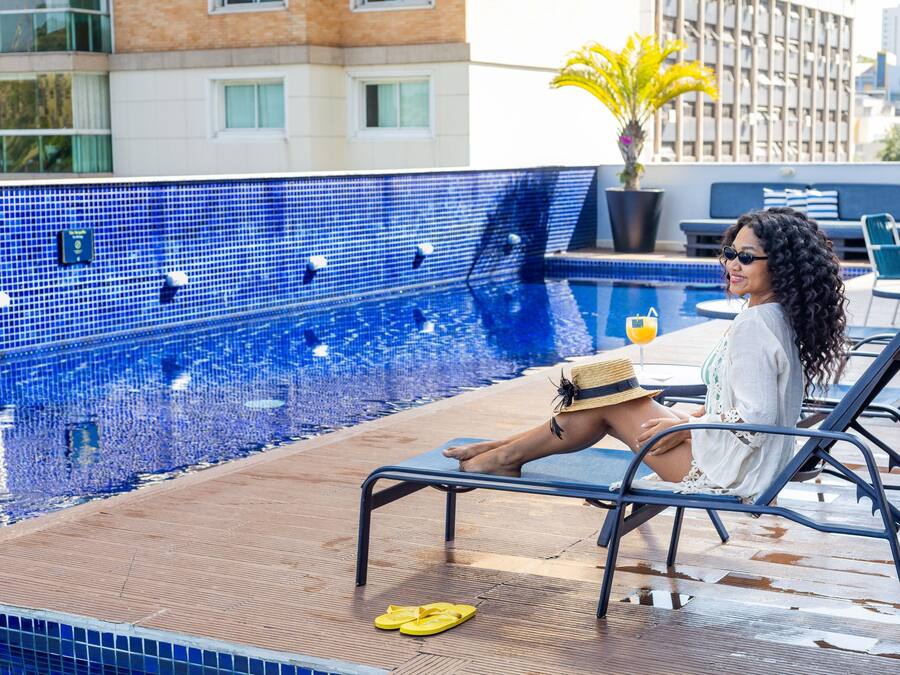A poolside area with a tiled pool, lounge chairs, and a potted plant.