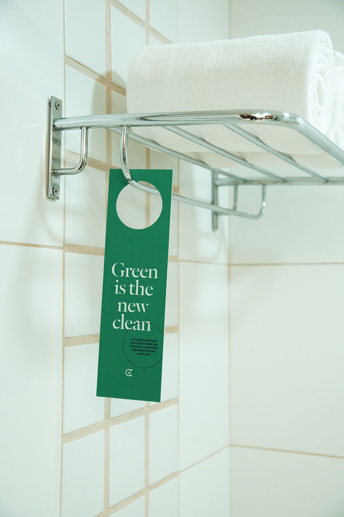 Un bagno con un portasciugamani che mostra un asciugamano bianco piegato e un cartellino verde con del testo.