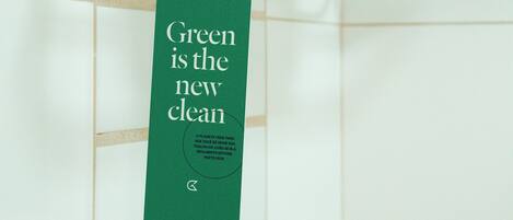 Un baño con un perchero que sostiene una toalla blanca doblada y una etiqueta verde con texto.