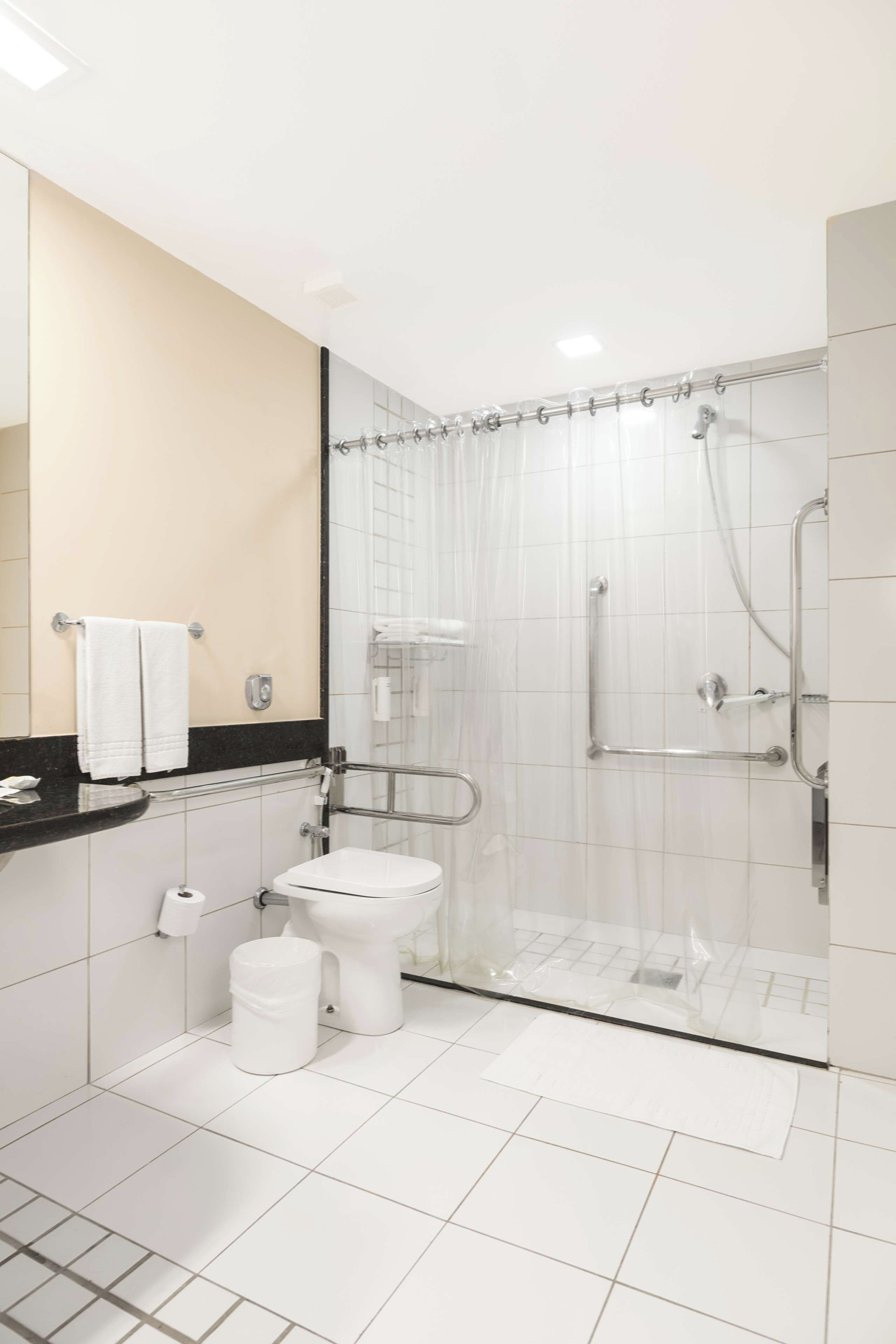 A modern bathroom with a toilet, shower, and a glass-enclosed shower stall.