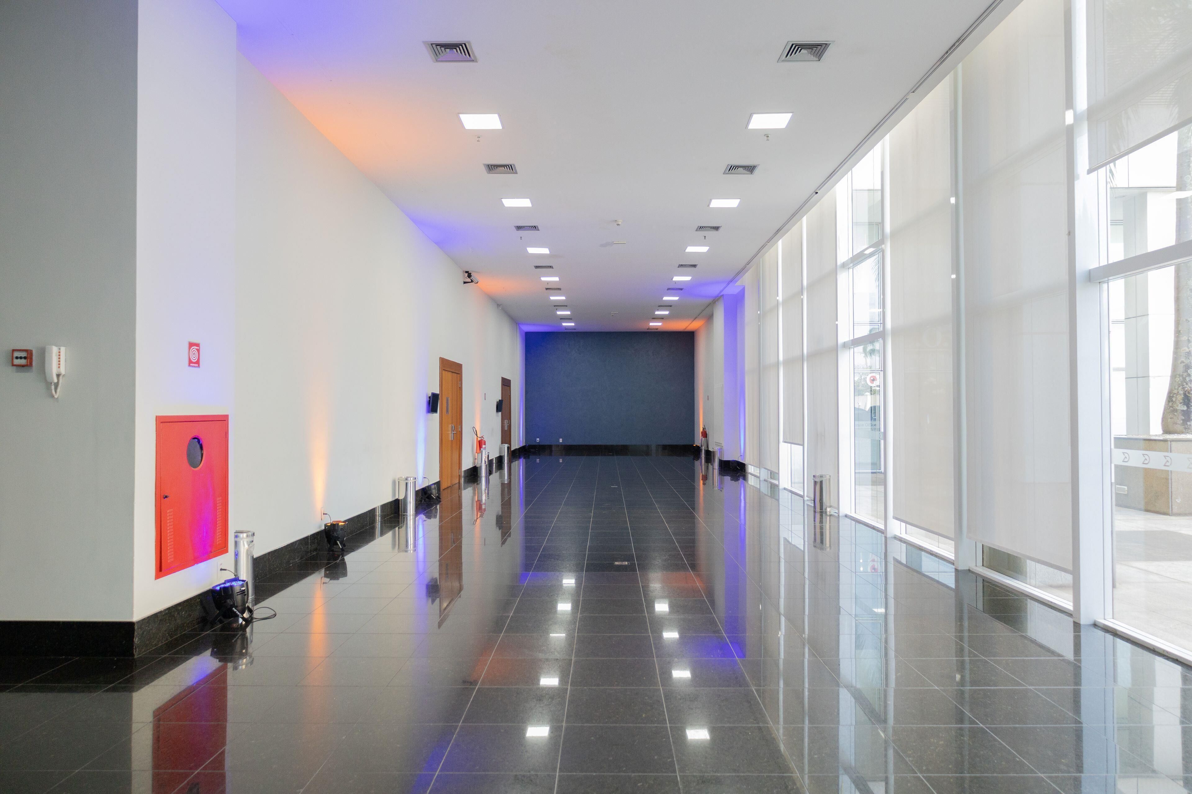 A clean, modern hallway with a shiny floor, large windows, and a blue wall at the end.
